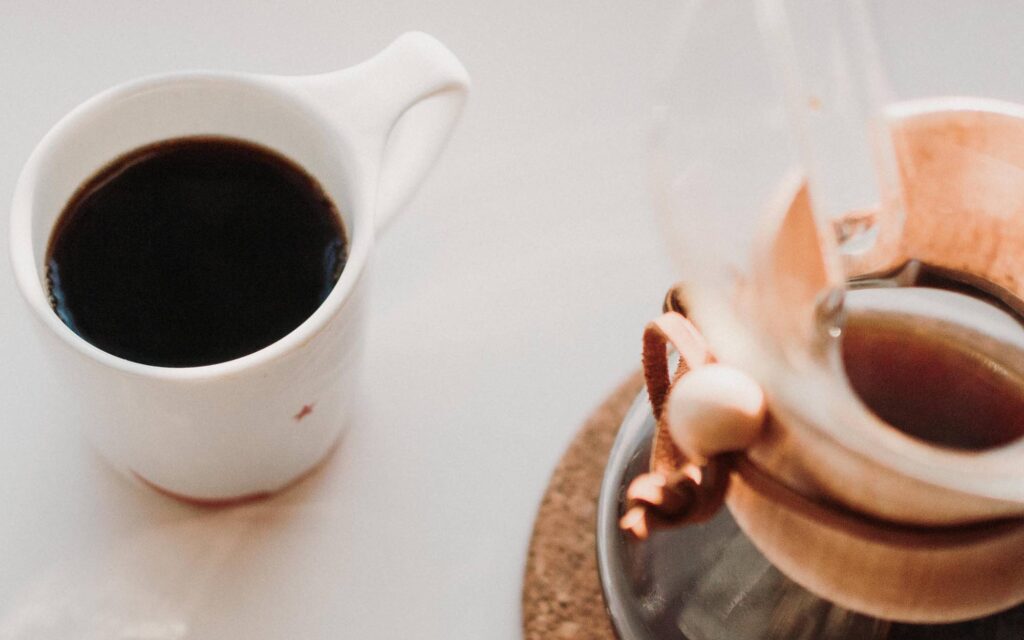 xícara de café ao lado de uma chemex